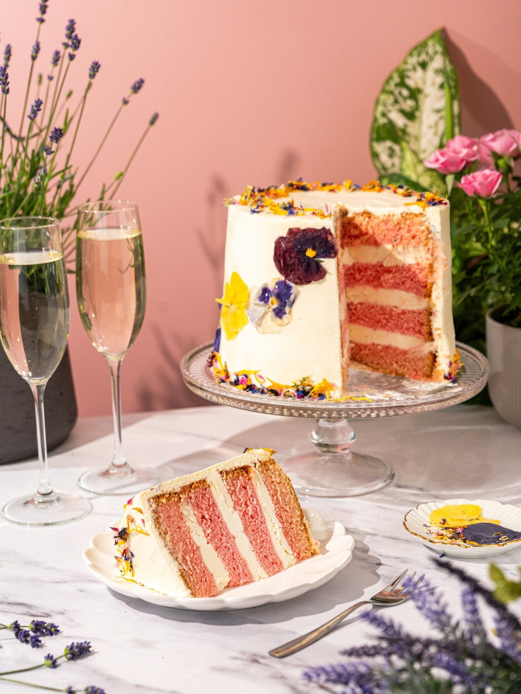 Patisserie Valerie's handmade Elderflower & Rose Garden Cake with edible flowers, being sliced and served
